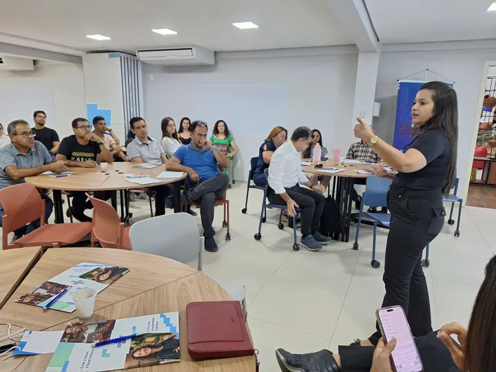 Participante conduz uma conversa com pessoas reunidas em mesas