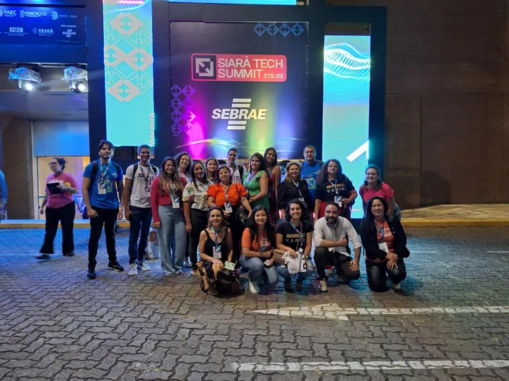 Grupo da comunidade reunido à noite em frente ao painel do Siará Tech Summit