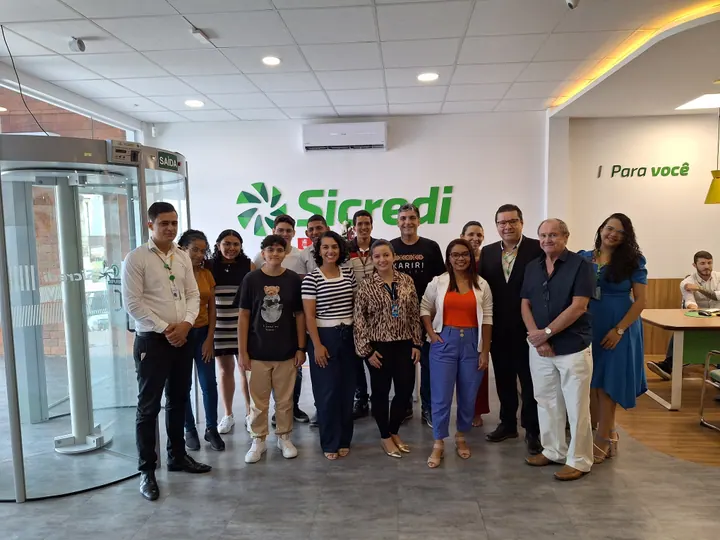 Grupo da comunidade reunido em frente a uma parede com a marca Sicredi