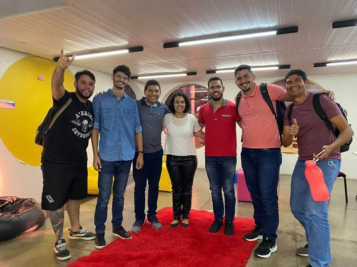 Grupo de participantes reunido sobre um tapete vermelho após uma atividade