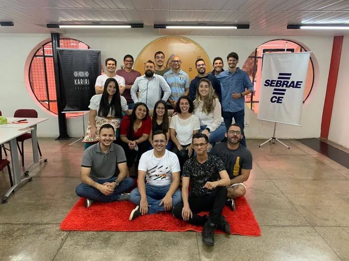 Grupo da comunidade posa entre painéis do Kariri Valley e do Sebrae