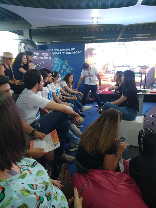 Pessoas sentadas em roda participam de uma conversa em um espaço aberto