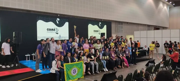 Grande grupo reunido sobre um palco, com os painéis Ceará Awards ao fundo
